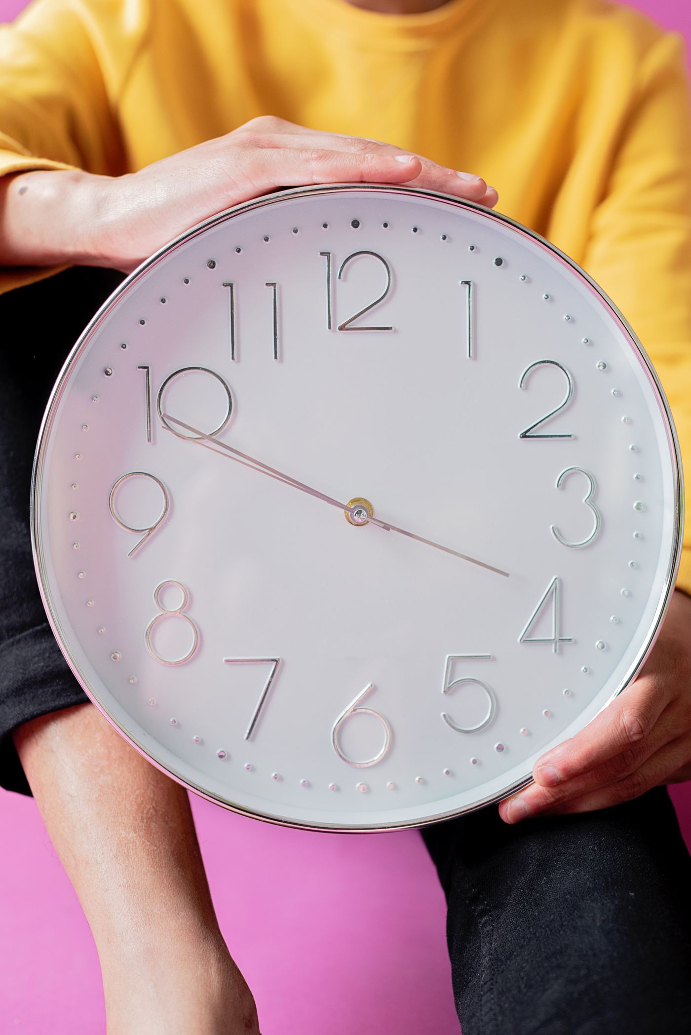 A person supporting a large round wall clock in both hands