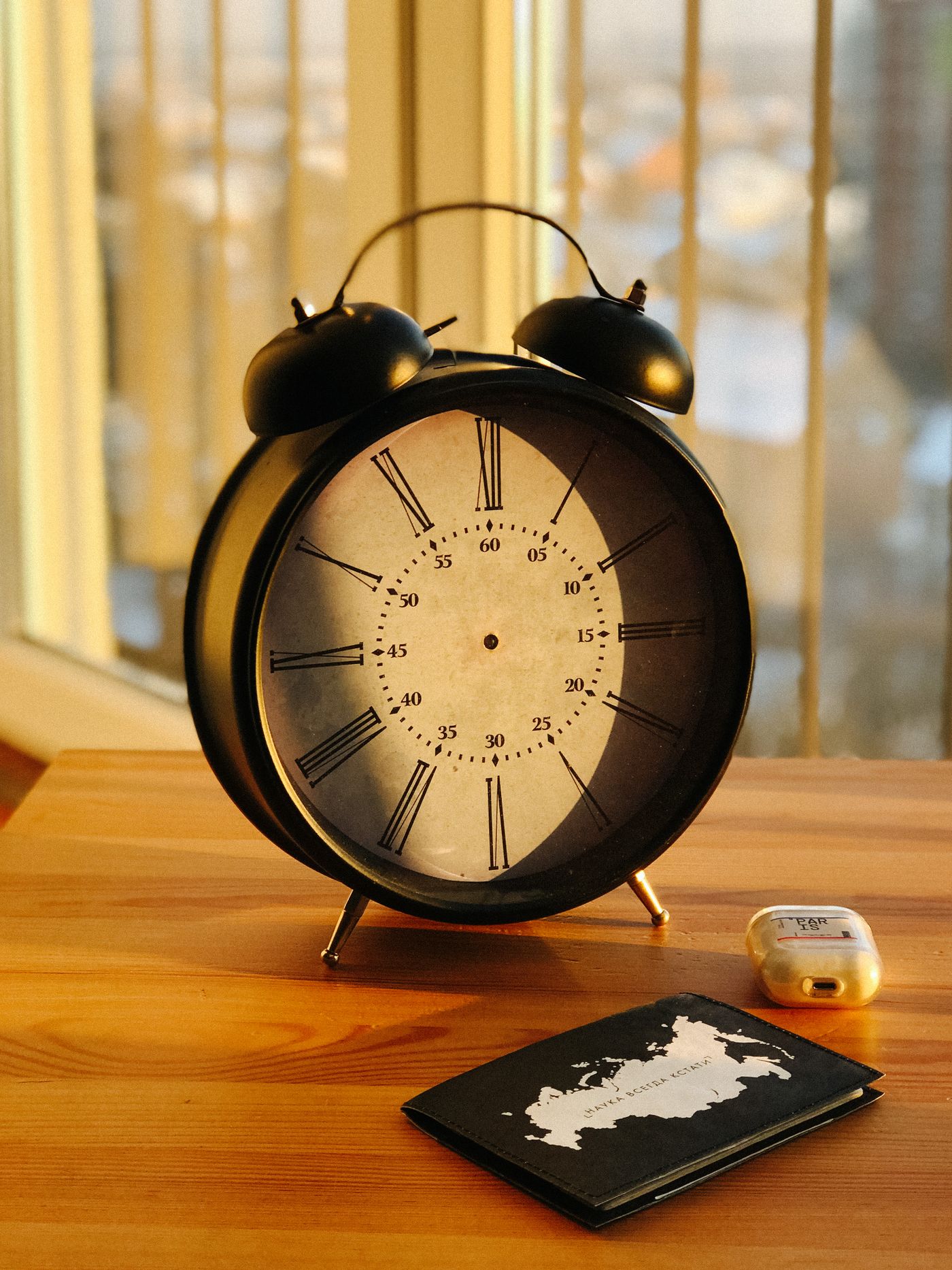 An alarm clock beside a passport and wireless earbuds