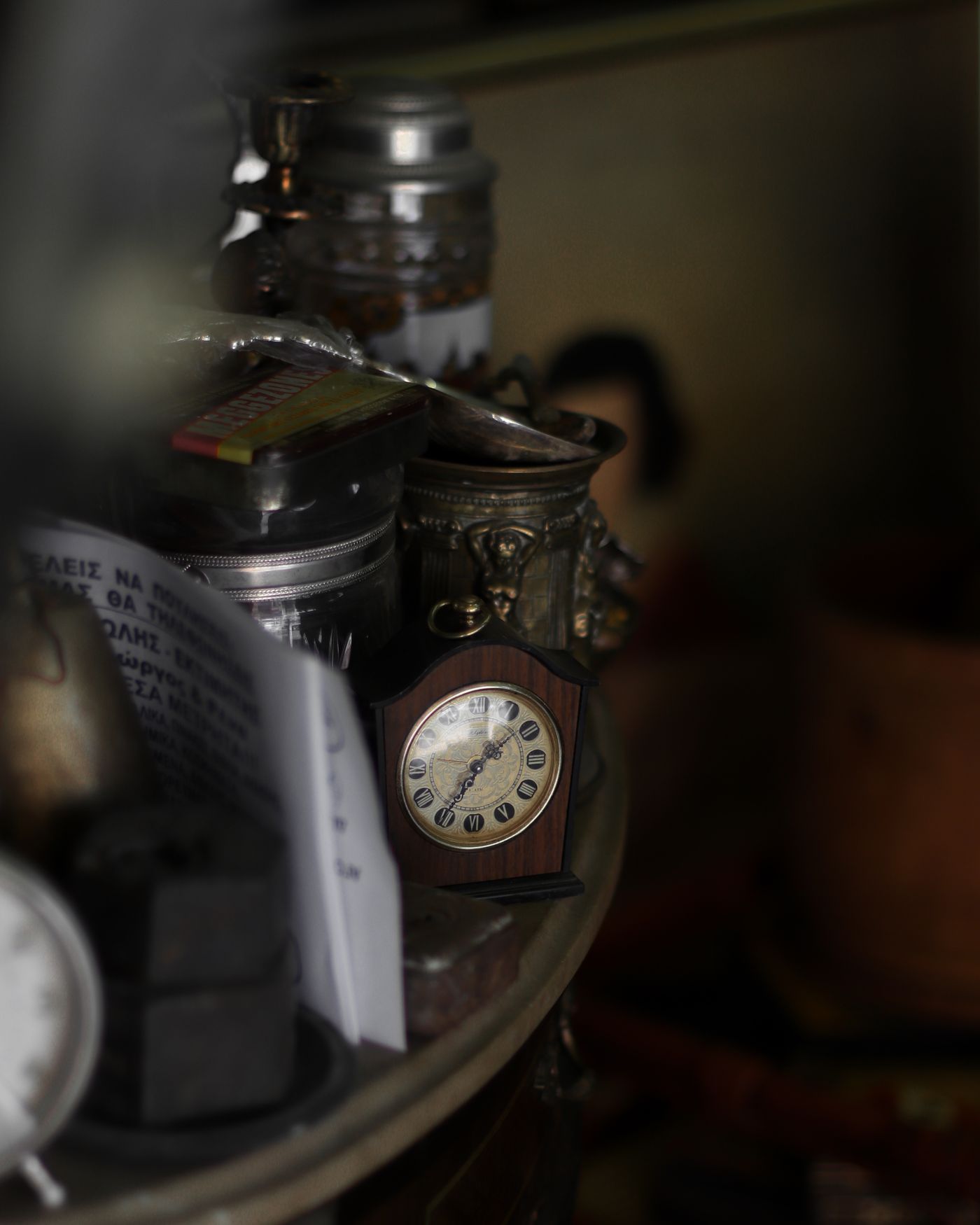 An aged wooden mantel clock among shelf objects