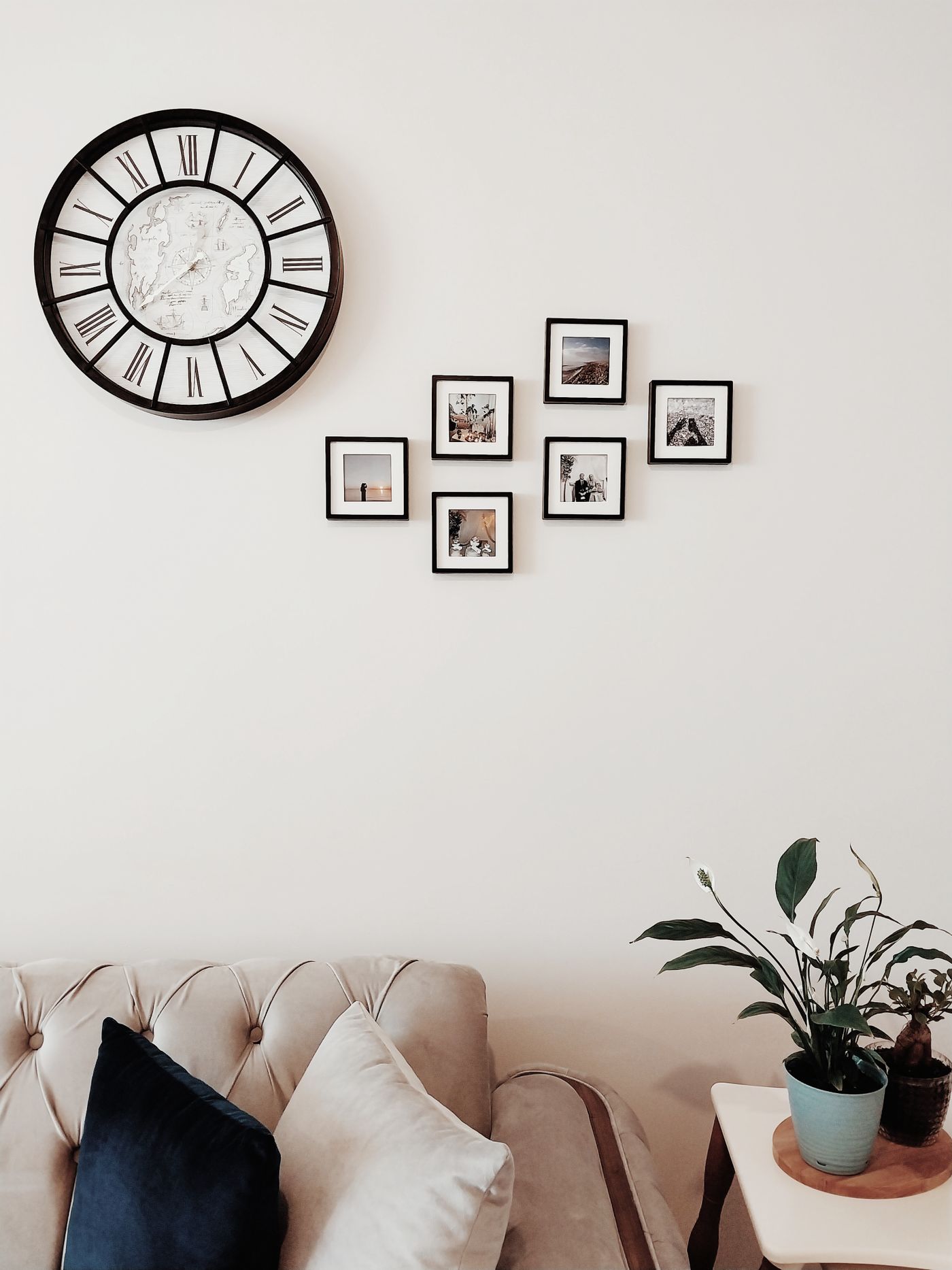 A large wall clock beside a group of small framed pictures